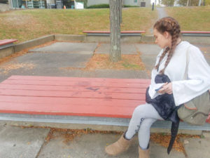 A student admires the “art bench” work sprawled on a bench located outside of Brahan Hall.